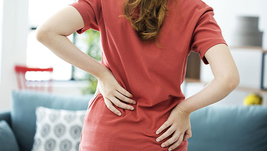 Woman holding lower back in pain before visiting Brentwood chiropractor